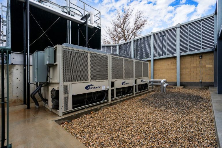 Modular commercial HVAC chiller system by Airstack in an outdoor industrial enclosure with a cooling tower background.